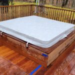 Large wooden hot tub with cover built into deck